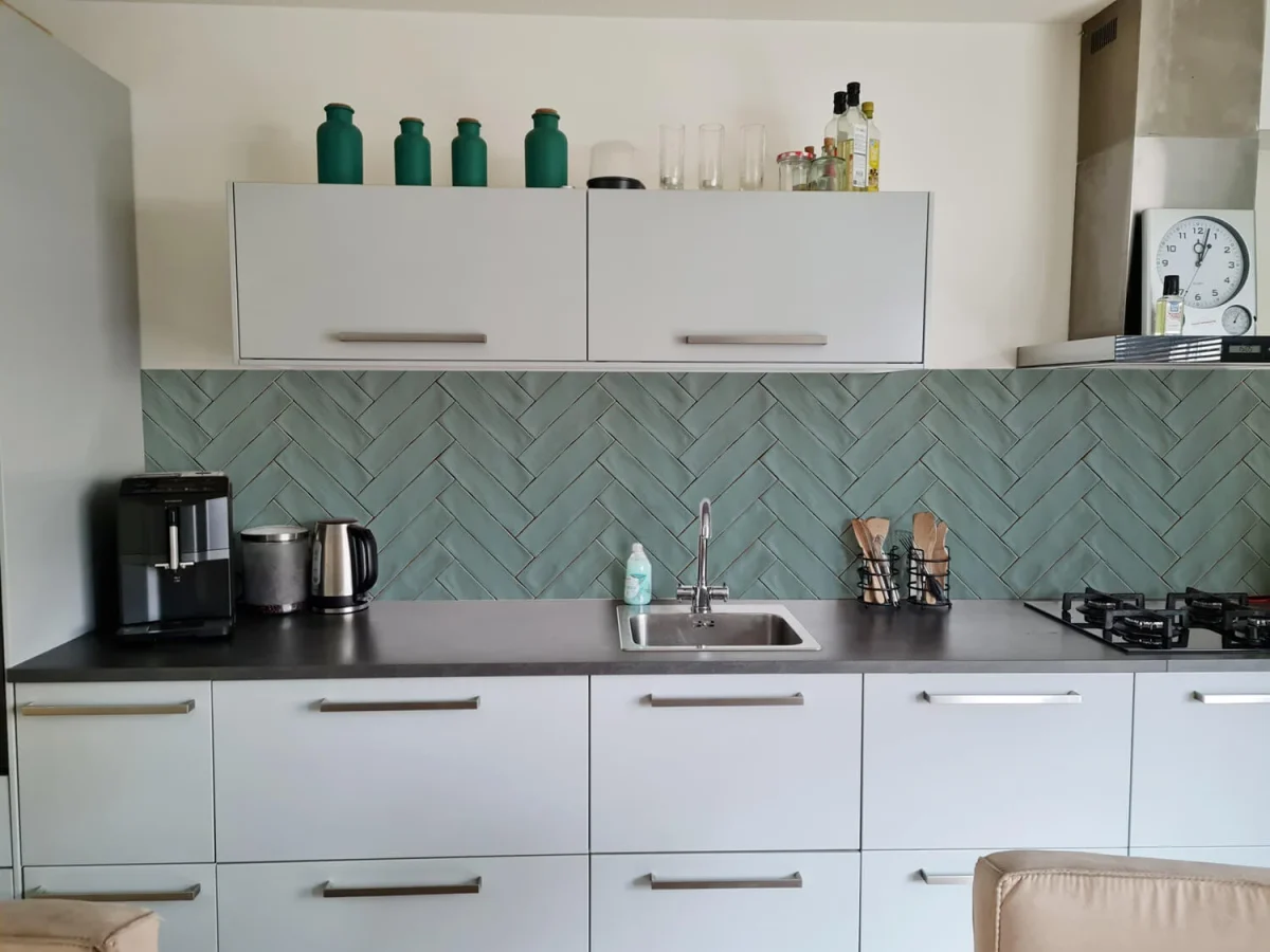 Green herringbone tile-look backsplash DW1058 with sea-green glaze effect installed in kitchen with white cabinets
