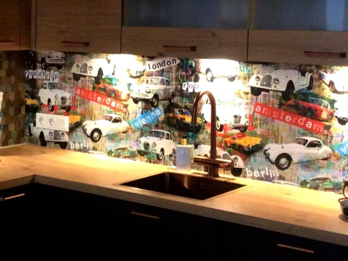 Keuken met kleurrijke pop-art spatwand met klassieke auto's en stadsbeelden van Amsterdam London en Berlin in donkere keuken