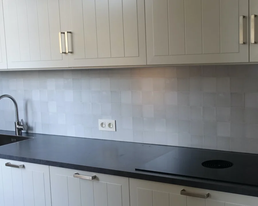 White Lilac antieke tegel spatwand in lichte lila tinten gemonteerd in keuken met witte kasten en donker werkblad