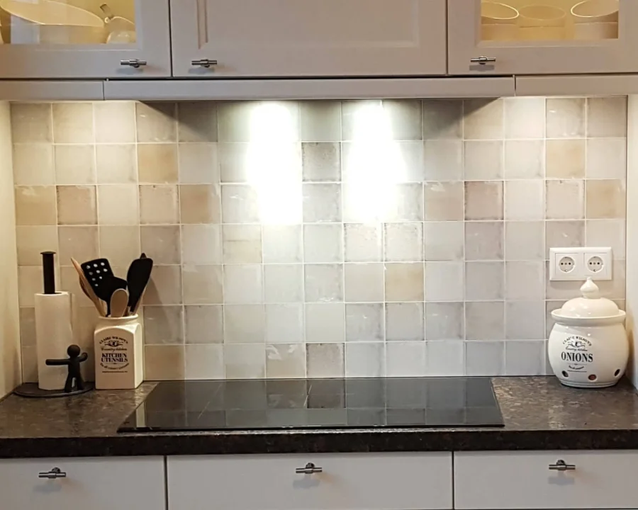 Swirl antieke tegel spatwand in crème en beigetinten in keuken met witte kasten en donker granieten werkblad