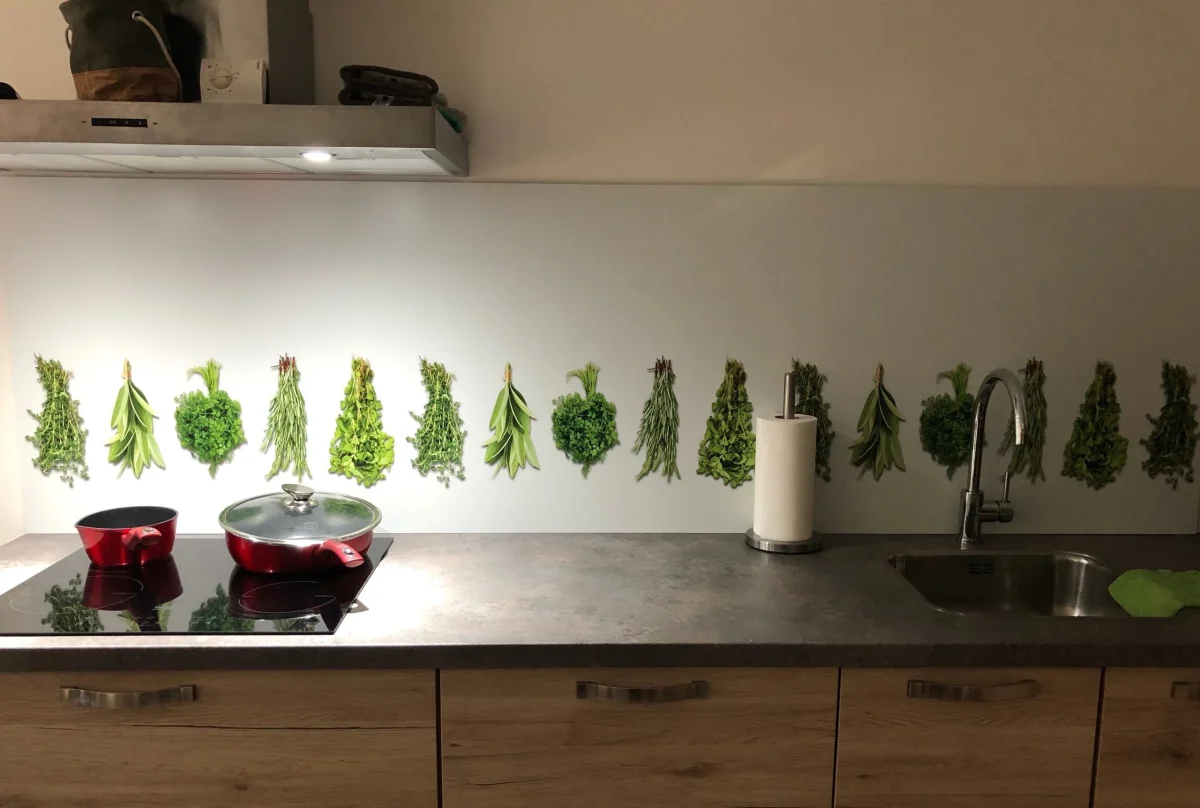 Spatwand met hangende verse kruidenbosjes op lichte achtergrond in keuken met houten fronten en donker werkblad FW1013