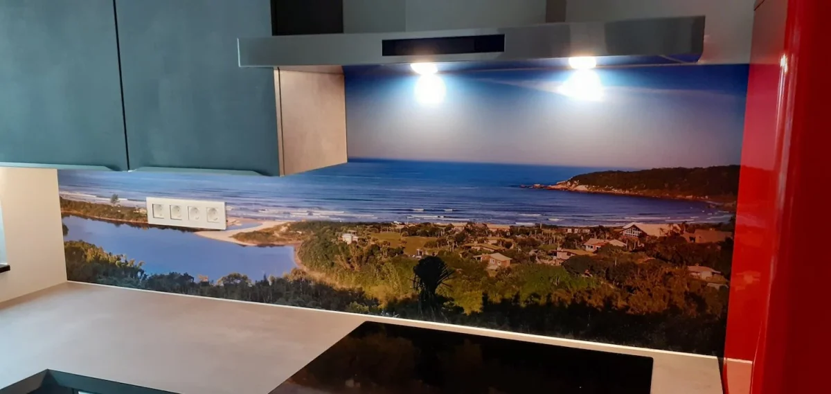 Kitchen with panoramic coastal photo backsplash featuring bay, sandy beach and green hills under blue sky