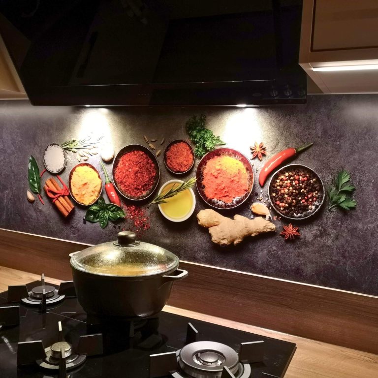 Crédence avec épices colorées dans des bols – paprika, curcuma, gingembre et poivre sur fond sombre derrière plaque à gaz