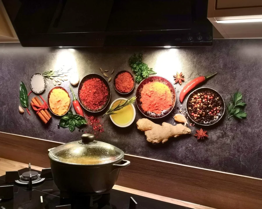 Spatwand met kleurrijke specerijen in schaaltjes – paprika, kurkuma, gember en peper op donkere achtergrond achter gaskookplaat
