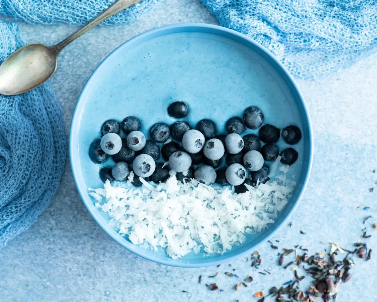 Blauwe gezonde smoothie bowl met bosbossen en kokos als foto voor op de achterwand van de keuken