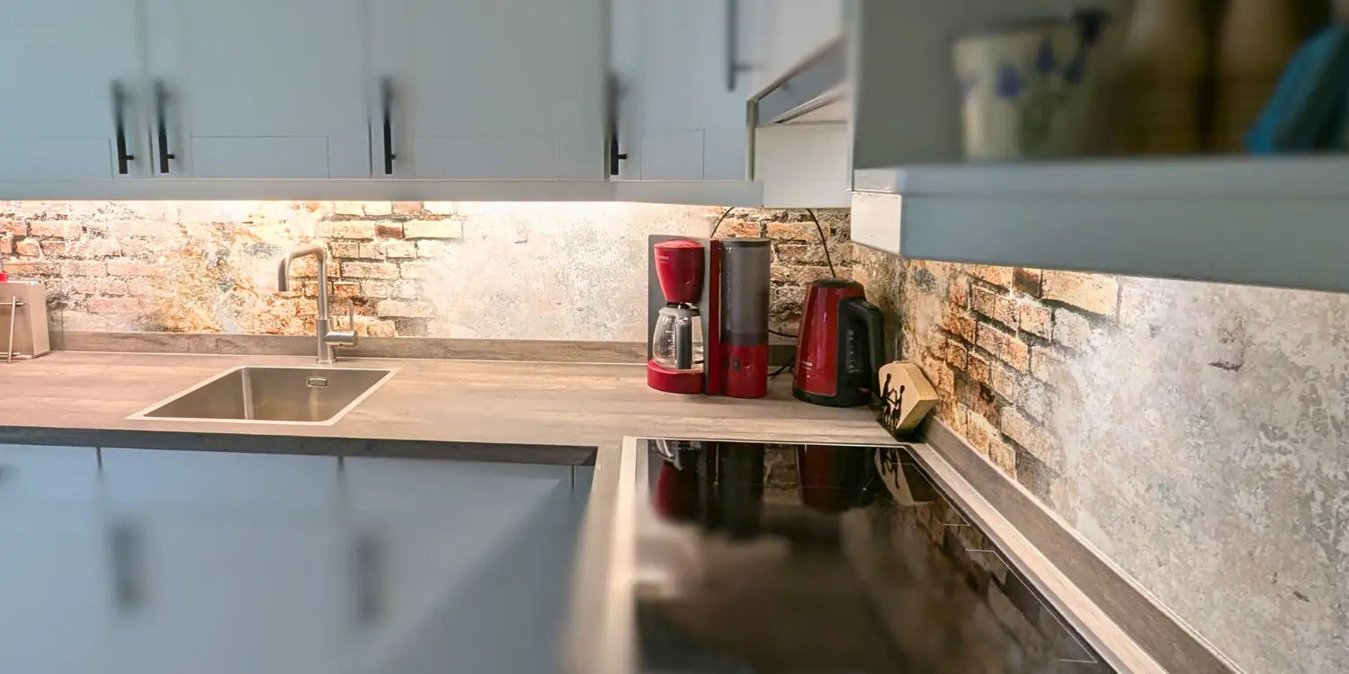 Breder uitzicht op de keuken met de nieuwe spatwand van Designerwand