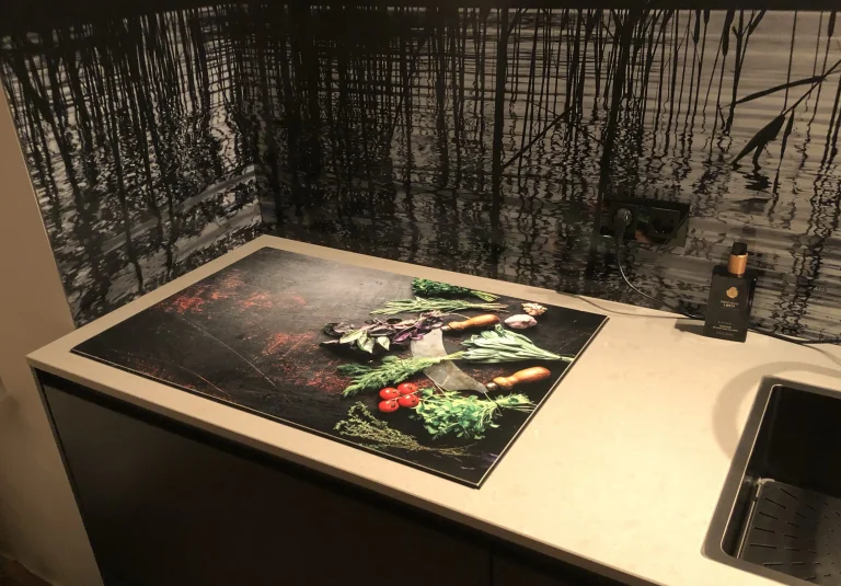 Inductiebeschermer kiezen: maat, materiaal en wat hij wel en niet kan 1 Keuken met een inductiebeschermer bedrukt met een eigen foto naast een donkere achterwand