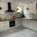 Portugiesische Fliesen Küchenrückwand Star Dust in einer L-förmigen cremefarbenen Küche mit Holzarbeitsplatte und rotem Kühlschrank