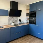 Portugiesische Fliesen Küchenrückwand Star Dust in einer blauen Küche mit Holzarbeitsplatte und schwarzer Dunstabzugshaube