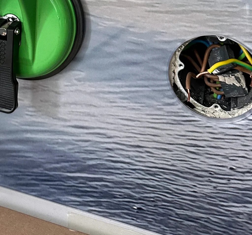 Socket cut-out in a glass kitchen backsplash, next to a suction lifter