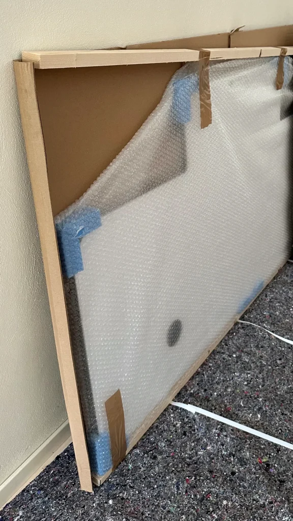 Glass kitchen backsplash in its packaging, with a wooden frame, bubble wrap and corner protectors